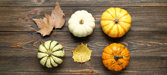 Composition with Halloween pumpkins and autumn leaves on wooden background, top view