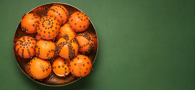 Plate of pomander balls on green background with space for text, top view