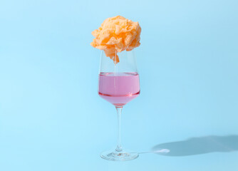 Glass with delicious cotton candy cocktail on blue background