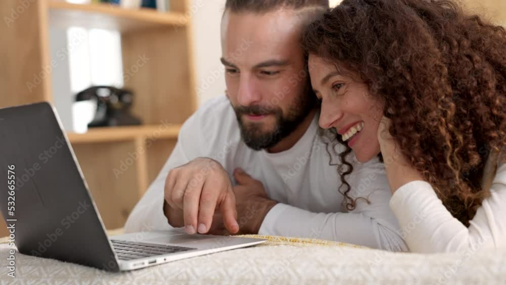 Poster Couple laptop, streaming movie and relax with comedy show on bed, reading social media notification on internet and happy with film on the web. Man and woman smile for video online in the bedroom