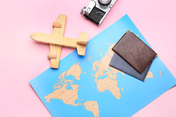 World map, photo camera and passports on pink background