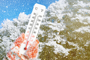 Winter holidays with snow. White celsius scale thermometer in hand. Ambient temperature minus 20 degrees celsius