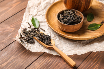 Composition with dry tea leaves on wooden background