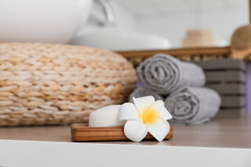 Obraz na płótnie Canvas Bar of soap and plumeria flower on table, closeup