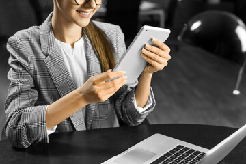 Smiling businesswoman working with tablet computer in office at night