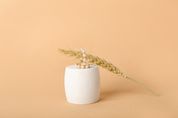 Showcase pedestal, wheat ear and earrings on beige background