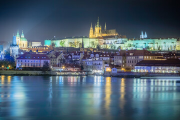 Fototapeta na wymiar Hradcany quarter and Vltava river at night with blurred boat movement, Prague