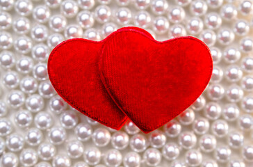 Two red hearts on the background of a pearl necklace