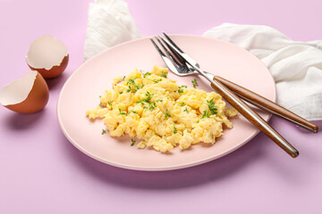 Plate of tasty scrambled eggs and shells on lilac background