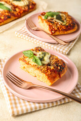 Plates of tasty Italian pie with mozzarella and pesto sauce on light table