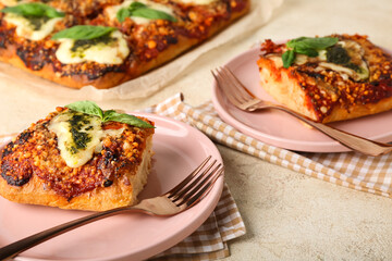 Plates of tasty Italian pie with mozzarella and pesto sauce on light table, closeup