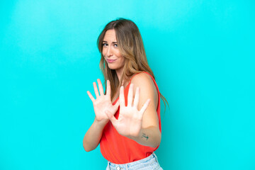 Young caucasian woman isolated on blue background nervous stretching hands to the front