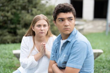 Obraz premium Teenager girl aking for forgiveness at angry boyfriend ignoring her. Couple relationship in adolescence concept.