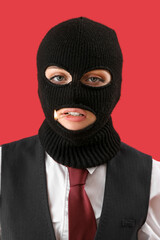 Portrait of young woman in balaclava with burning match in mouth on red background