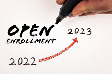 Open Enrollment. Text and a man's hand holding a black marker on a white background