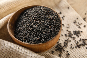 Wooden bowl of black sesame seeds on table, closeup