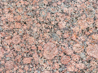 Granite texture. Natural pink granite with a grainy pattern. Stone background. Solid rough surface of rock. Durable construction and decoration material. Close-up.