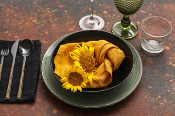 Trendy dinnerware and beautiful sunflowers on color background