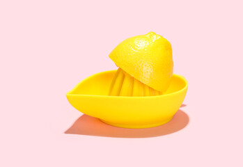 Juicer with half of fresh lemon on pink background