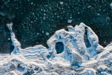 Top view of the freezing sea. Winter aerial photograph of the icy coast and ice floes in sea water....