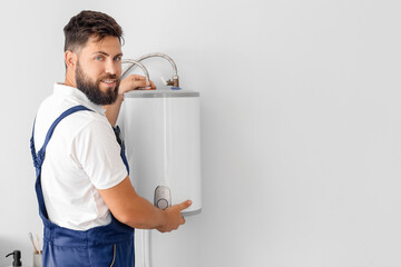 Male plumber installing boiler in bathroom