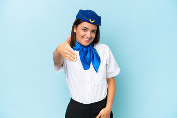 Airplane stewardess caucasian woman isolated on blue background shaking hands for closing a good deal