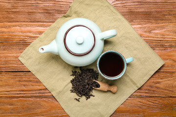 Napkin with scoop of dry puer tea, cup and teapot on wooden background