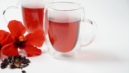 A transparent glass  with hot red carcade floral tea
