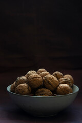 Bowl full of walnuts on black background with copy space
