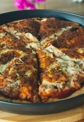 Tasty pizza with melting buffalo mozzarella, delicious tuna and green pepper. Tasty fast food traditional on wooden board table.