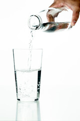 Detail of an unrecognizable man's hand pouring water into a crystal glass on a white background.