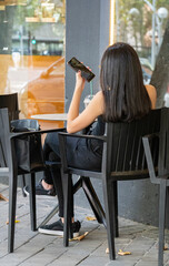 Young girl talking on phone from abroad with her family or friend, holding smartphone speaking, sitting at table 