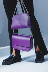 A purple leather bag in a girl's hand. Woman with luxury bag.