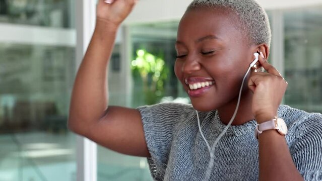 Employee, earphones and listening to music while dancing in an office. Happy, excited and black woman with smile, dance and relax on work break with mobile device in corporate business building