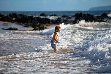 Boy kid jumping in sea waves. Jump by water sea splashes. Summer kids vacation.