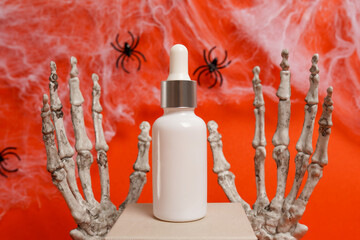 Cosmetic white glass bottle oil with pipette staying on the podium with halloween decorations...
