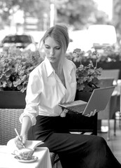 Black and white photo with Elegant business lady manager makes notes in a notebook in a summer cafe. Meeting. Marketing. Business concept.
