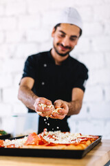 Italian chef pizzaiolo putting mozzarella cheese on pizza