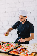 Italian chef pizzaiolo making sicilian pizza in restaurant kitchen - obrazy, fototapety, plakaty
