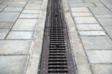 Fototapeta na wymiar Drainage system with stainless steel composite grating between paving slabs.