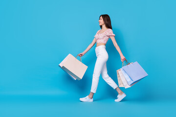 Full length profile side photo of nice lady shopaholic look empty space slim figure stylish outfit isolated on blue color background