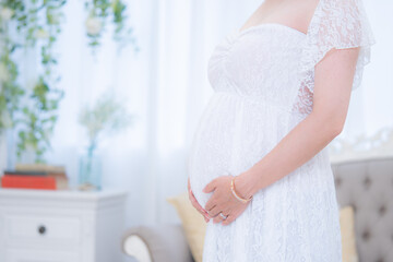 マタニティドレスでお腹に手をそえる妊婦...