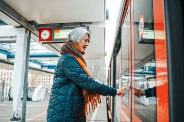 Senior woman press the button to open the door of the train