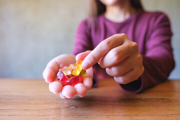 Closeup image of a woman holding and picking up a jelly gummy bear