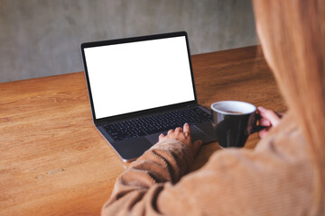 Mockup image of a woman using and typing on laptop computer with blank white desktop screen while drinking coffee