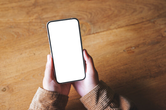Top view mockup image of a woman holding mobile phone with blank desktop screen