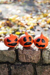 Scary halloween pumpkins on a brick fence in the suburbs against the backdrop of autumn foliage.