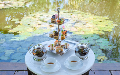 Afternoon tea at a water pond, high tea in a tropical garden in Thailand. 