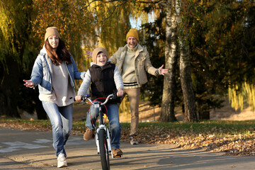 family on a walk in the park. boy on bike and happy parents
