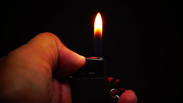firelight. gas lighter videos. close-up fire from the lighter igniting in the hand in the dark on a black background. Man's hand with gas lighter. 4K videos.